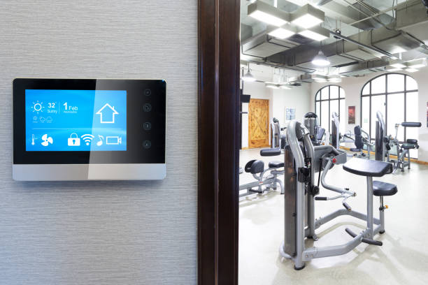 Smart home gym setup with modern exercise equipment and a wall-mounted digital control panel for easy management.